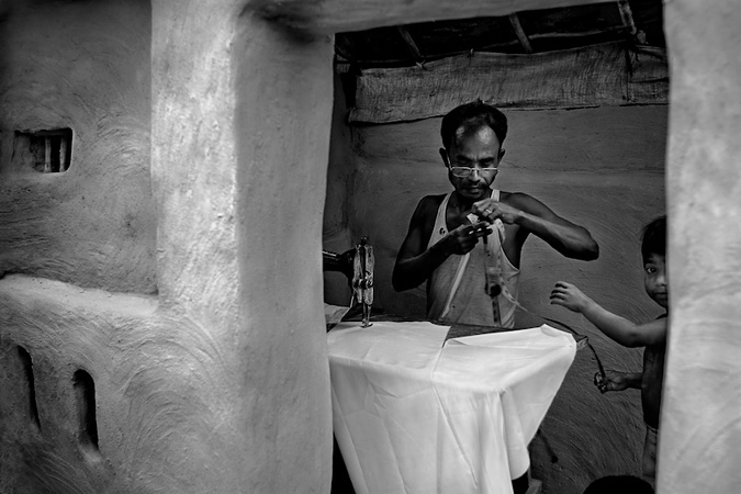 Man sewing while a boy helps