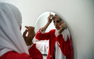 A woman fixes her scarf in a mirror.