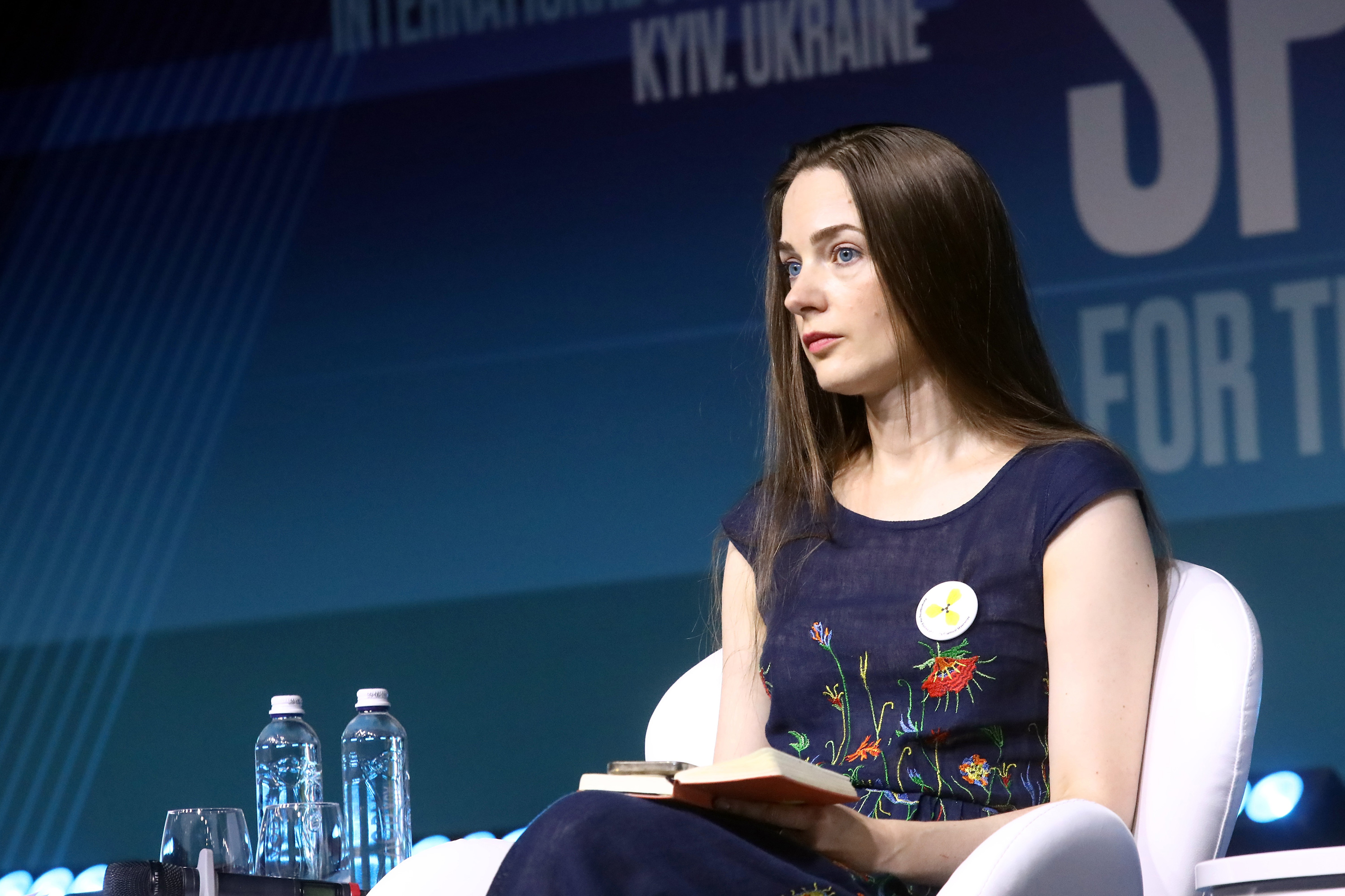 A woman sits on stage for a panel event