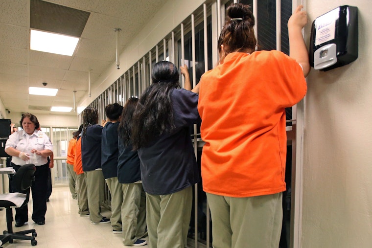 A line of female inmates in front of prison cells