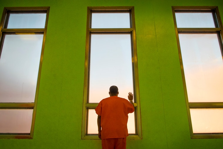 A man in orange standing at a window