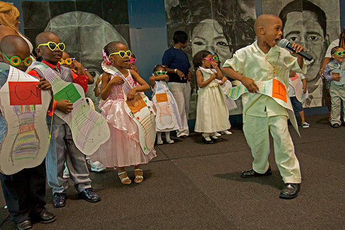 Kids wearing paper guitars and singing.