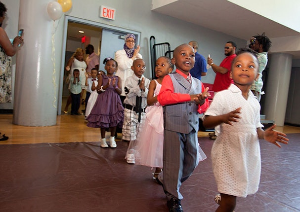 Children dressed up and walking into a gym.