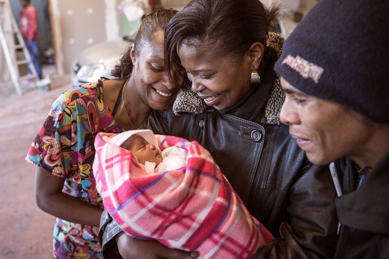 People looking at a sleeping newborn baby