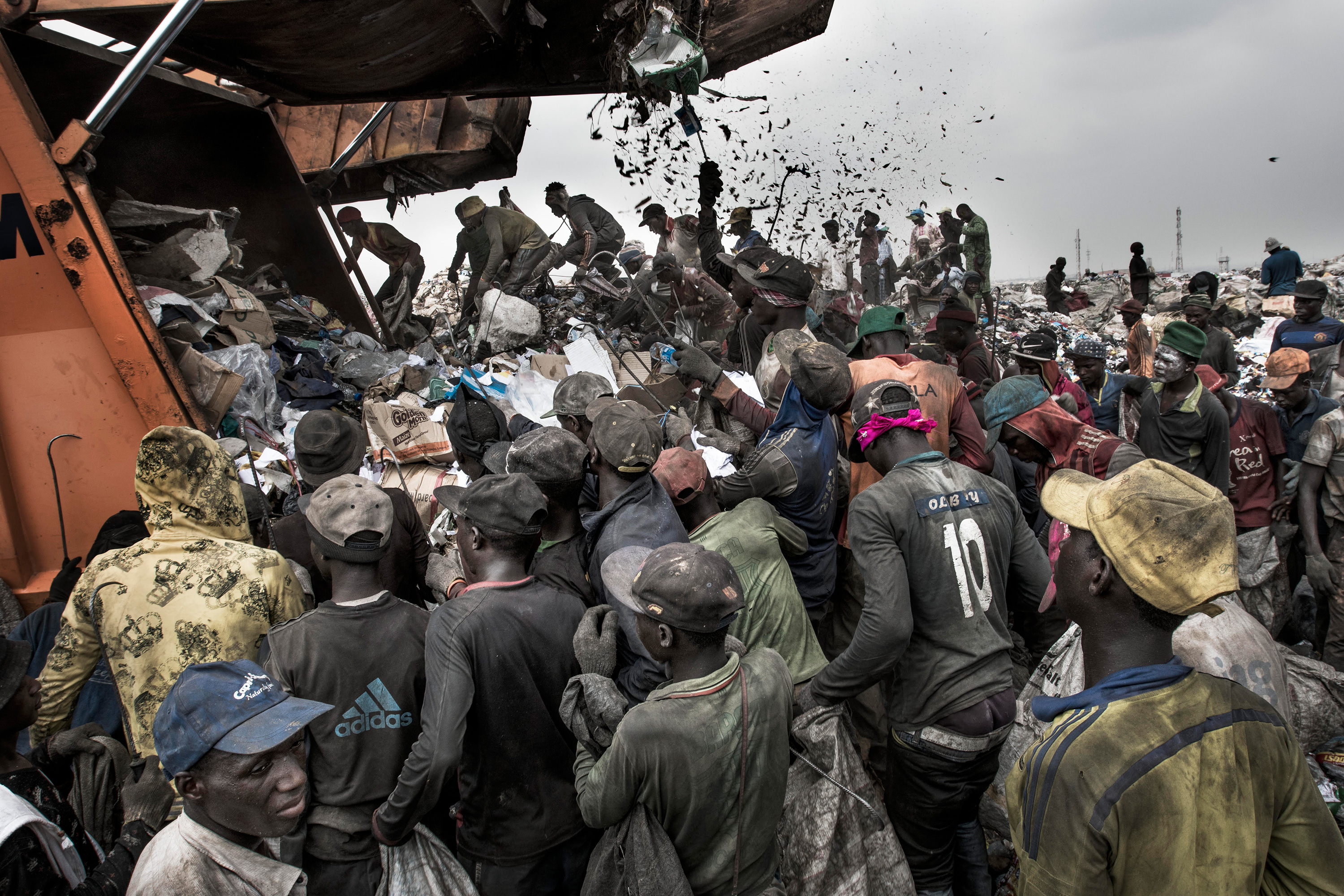 A large group of people crowd around a garbage truck