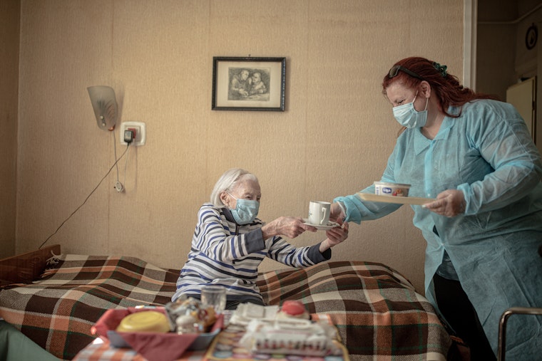 A social worker visits an elderly woman in Budapest, Hungary, on May 21, 2020. Photo credit: © Akos Stiller/Redux A social worker visits an elderly woman