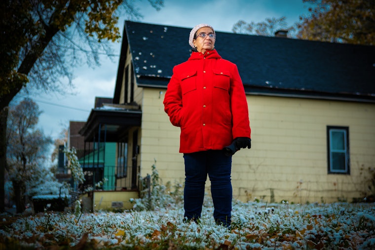 Dennice Barr in a red coat standing outside her home