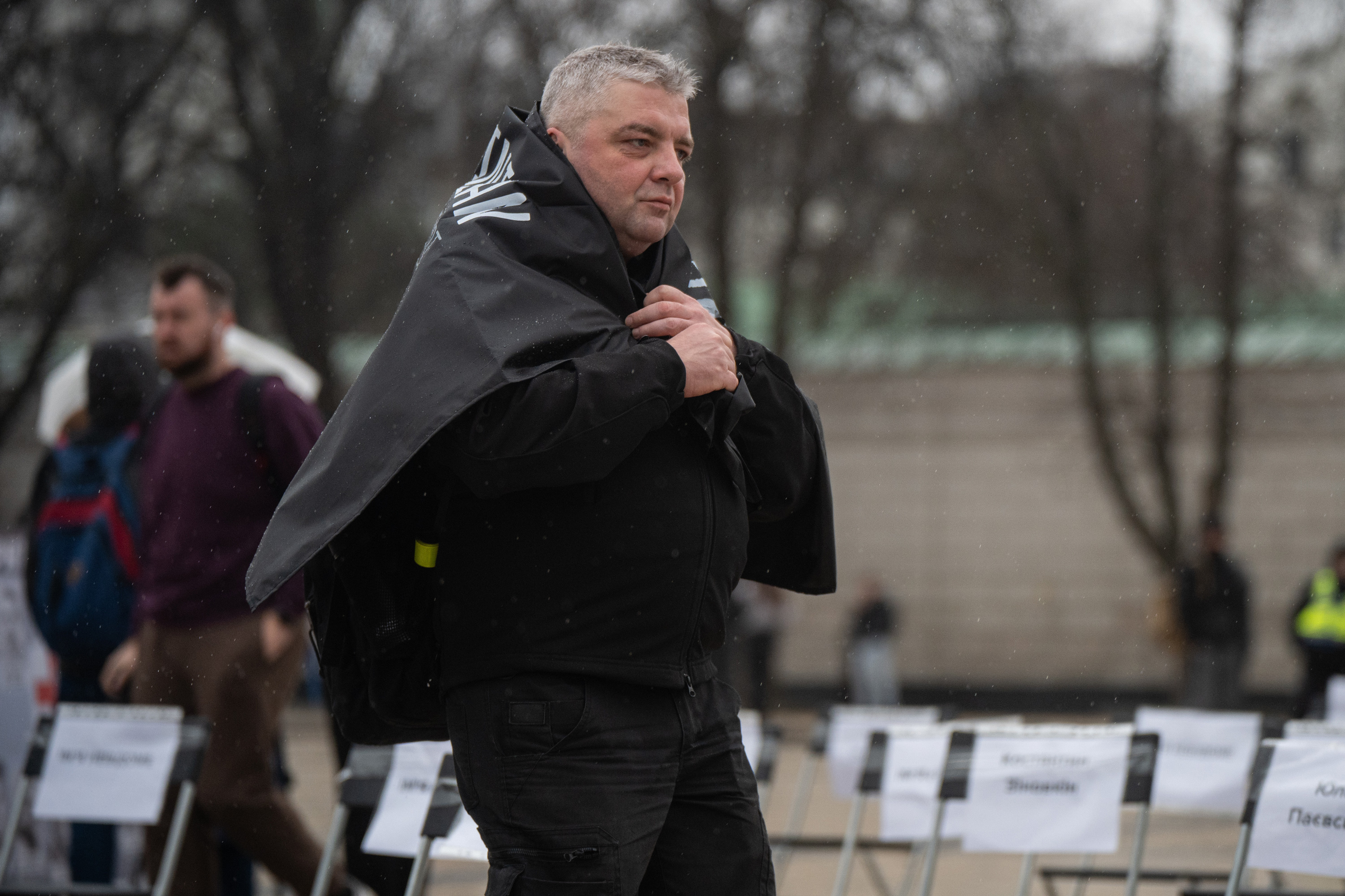 A man stands with a flag wrapped around his shoulders