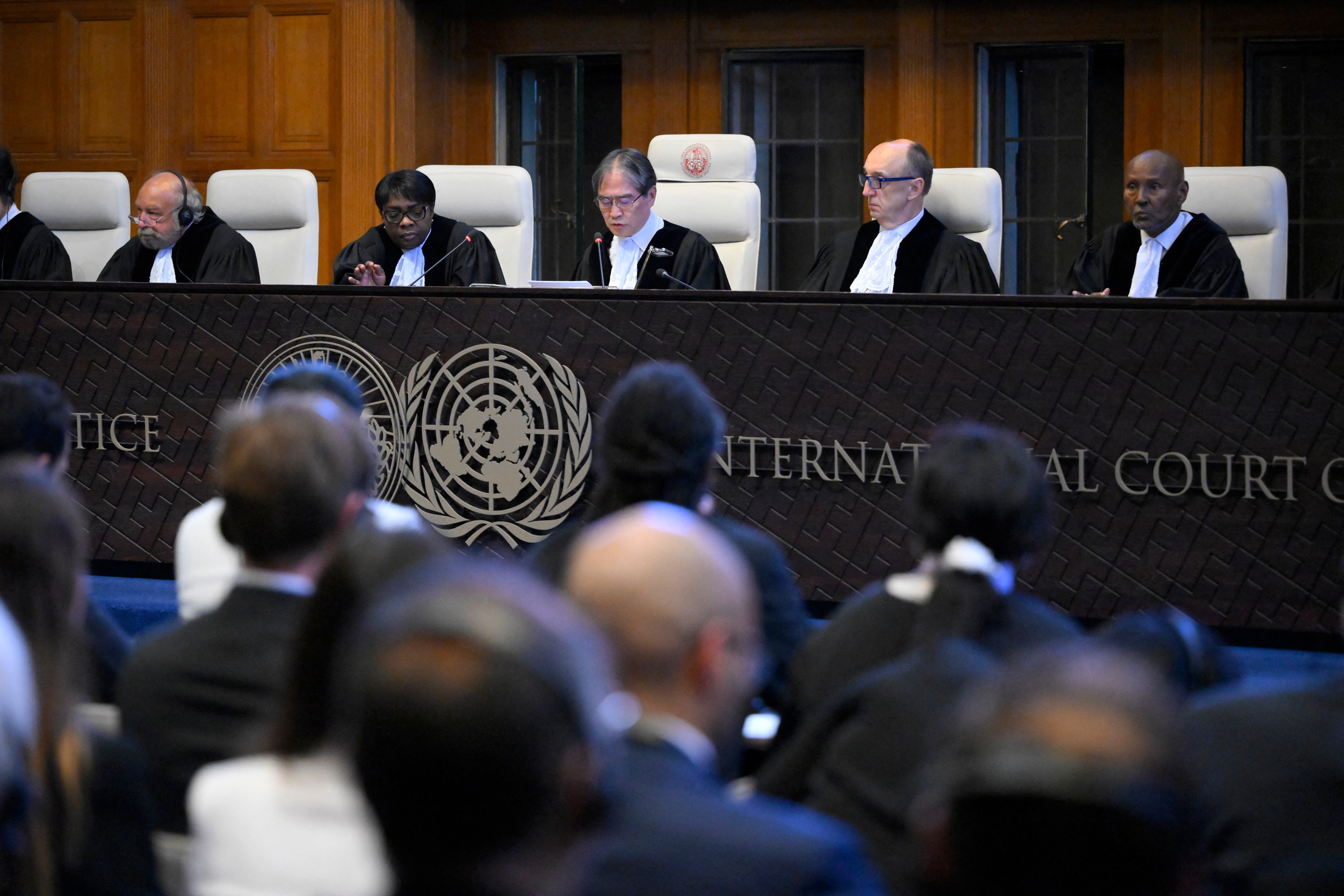 A group of five judges sit on a stage