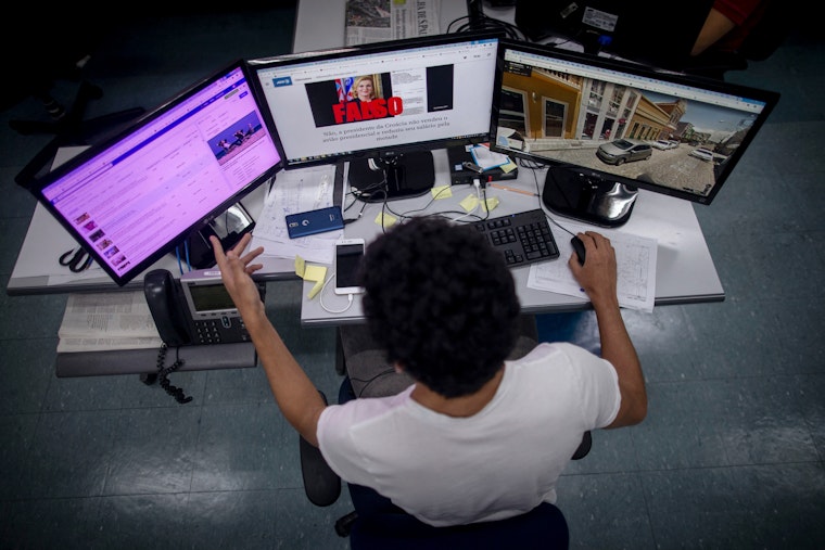 A person at a desk looking at several monitors