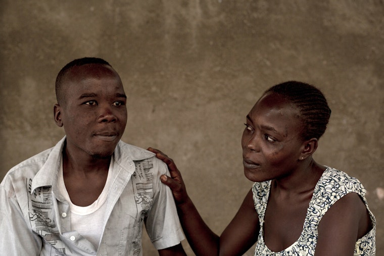 A brother is comforted by his sister as he enrolls in a methadone program in Mombasa, Kenya. Photo credit: © Roopa Gogineni for the Open Society Foundations A woman rests her hand in a comforting way on a man's shoulder.