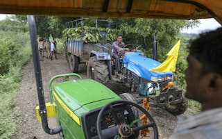 Men driving tractors on a dirt road