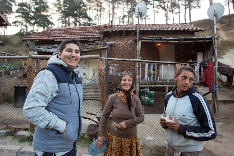 A health mediator visits with two members of the local Roma community in Sofia, Bulgaria on September 28, 2016. Photo credit: © Boryana Katsarova for the Open Society Foundations A man stands outside a house with two women.