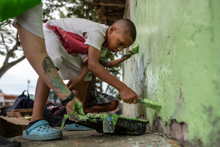 Un niño sosteniendo un pincel contra una pared