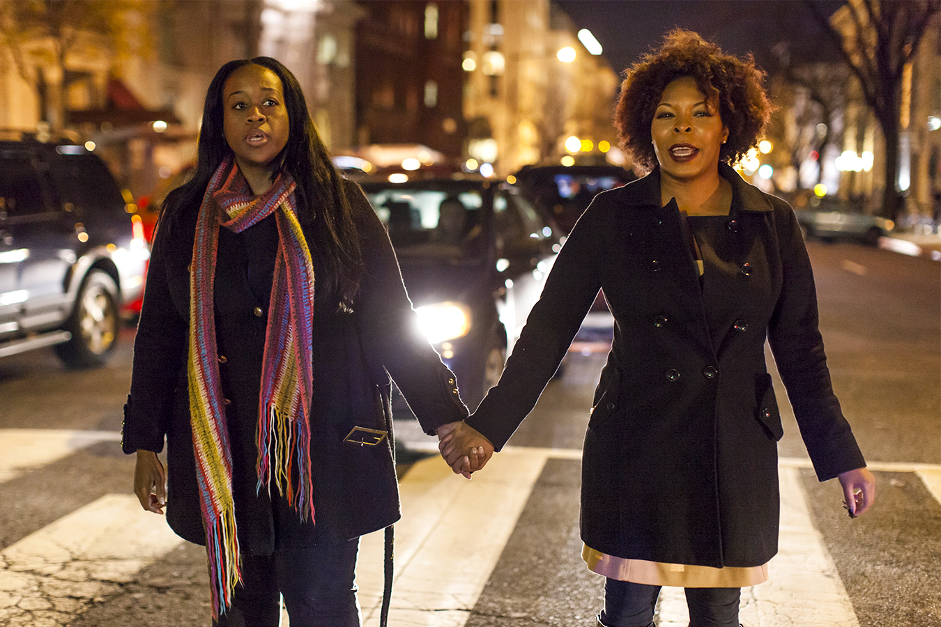 Women hold hands outside