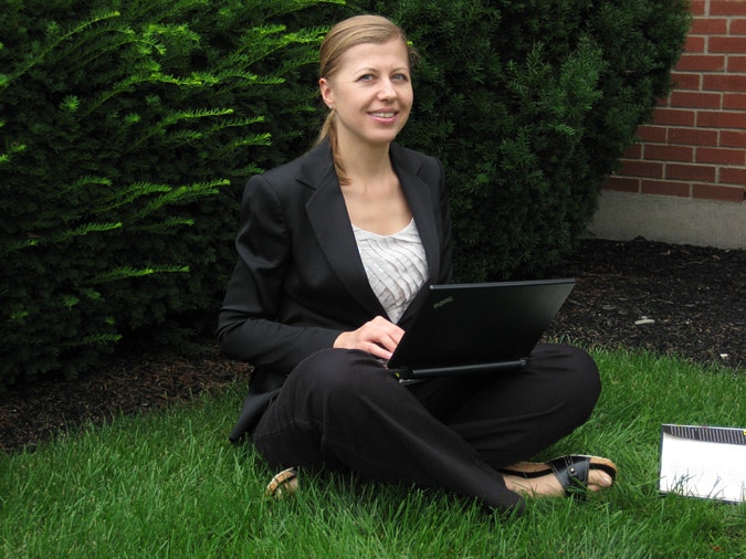 Maria Creciun sitting on the grass with a laptop