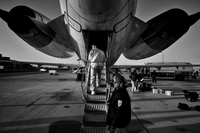 While chained in restraints, a migrant from Honduras boards a plane to be deported back home at the Phoenix airport in Arizona. Every day, there are five to nine flights to Central America. Photo credit: © Kadir van Lohuizen/NOOR Man boarding plane