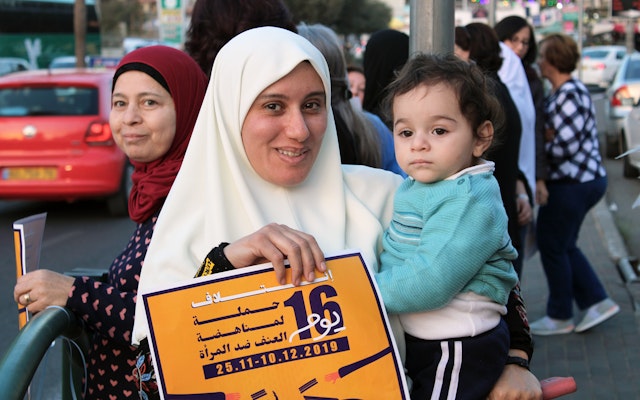 Woman holding a young child and a sign