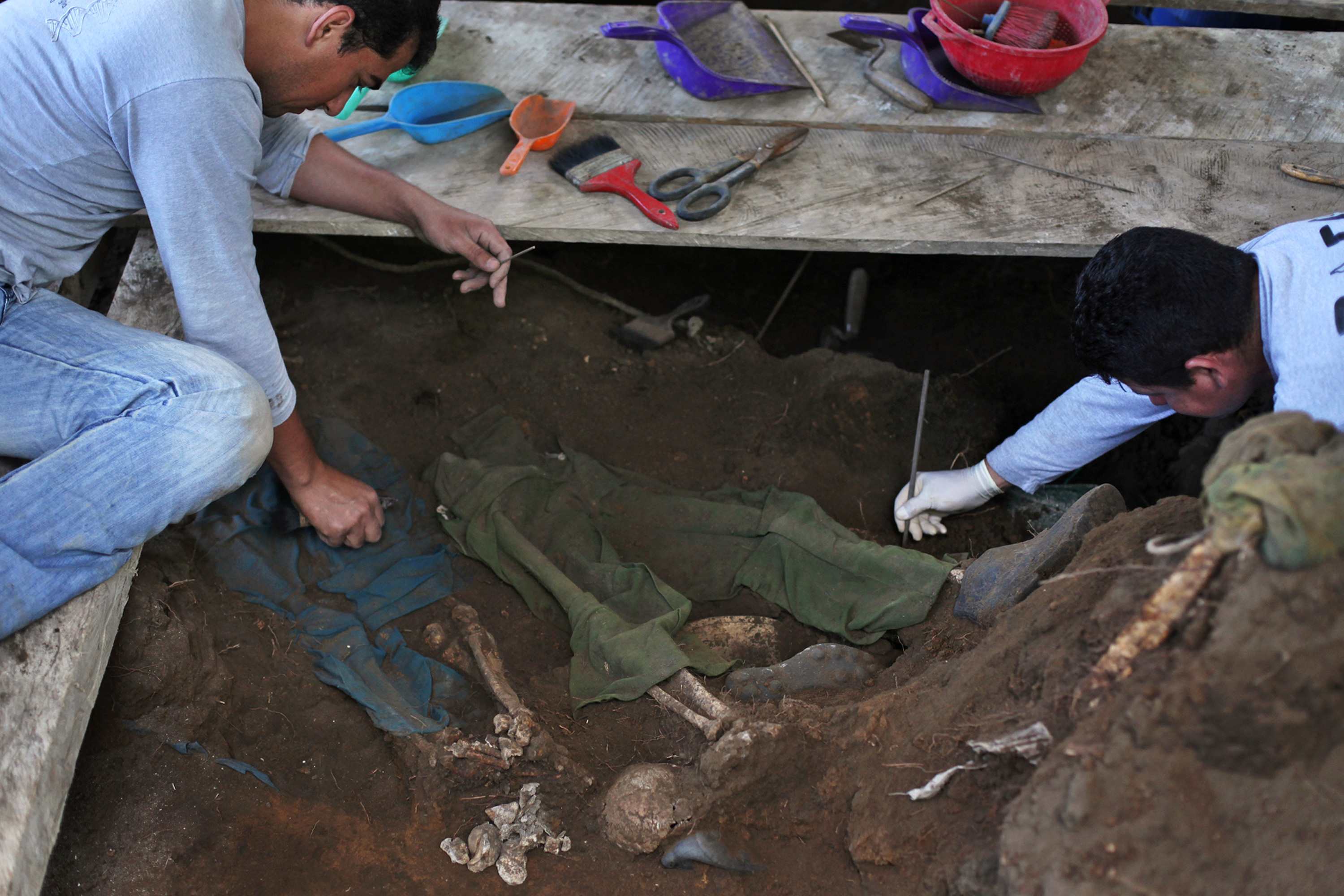 Two people clearing dirt from skeletal remains