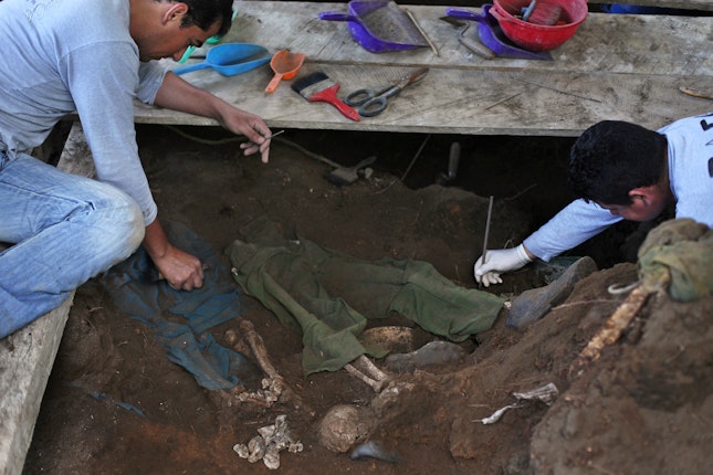 Two people clearing dirt from skeletal remains