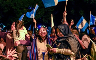 A woman smiles at the camera among people celebrating the results of an election in Guatemala.