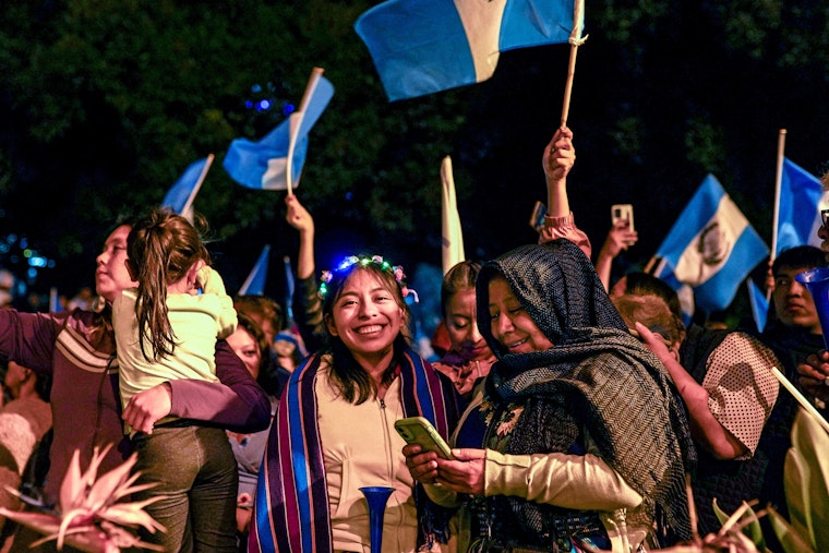 A woman smiles at the camera among people celebrating the results of an election in Guatemala.
