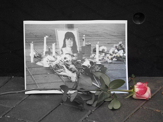 Vigil; rose in front of a photograph of a woman&#039;s picture surrounded by candles