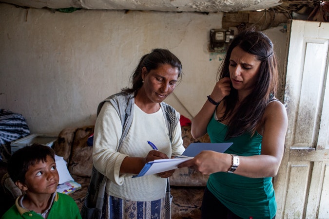 Romina Kajtazova, a Roma paralegal with the Humanitarian and Charitable Association of Roma, talks with Ljutvia Demyrova, a mother of eight children at her home in Vinica, Macedonia during the European Immunization Week. Photo credit: © Bjorn Steinz/Panos Pictures for the Open Society Foundations two women and a boy