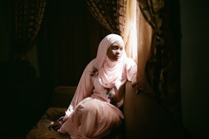 Farida Ado, 27, a romance novelist living in northern Nigeria, is pictured at her window in April 2014. She’s one of a small but significant group of Nigerian women writing books called Littattafan soyayya, Hausa for “love literature.” Photo credit: © Glenna Gordon Young woman in pink