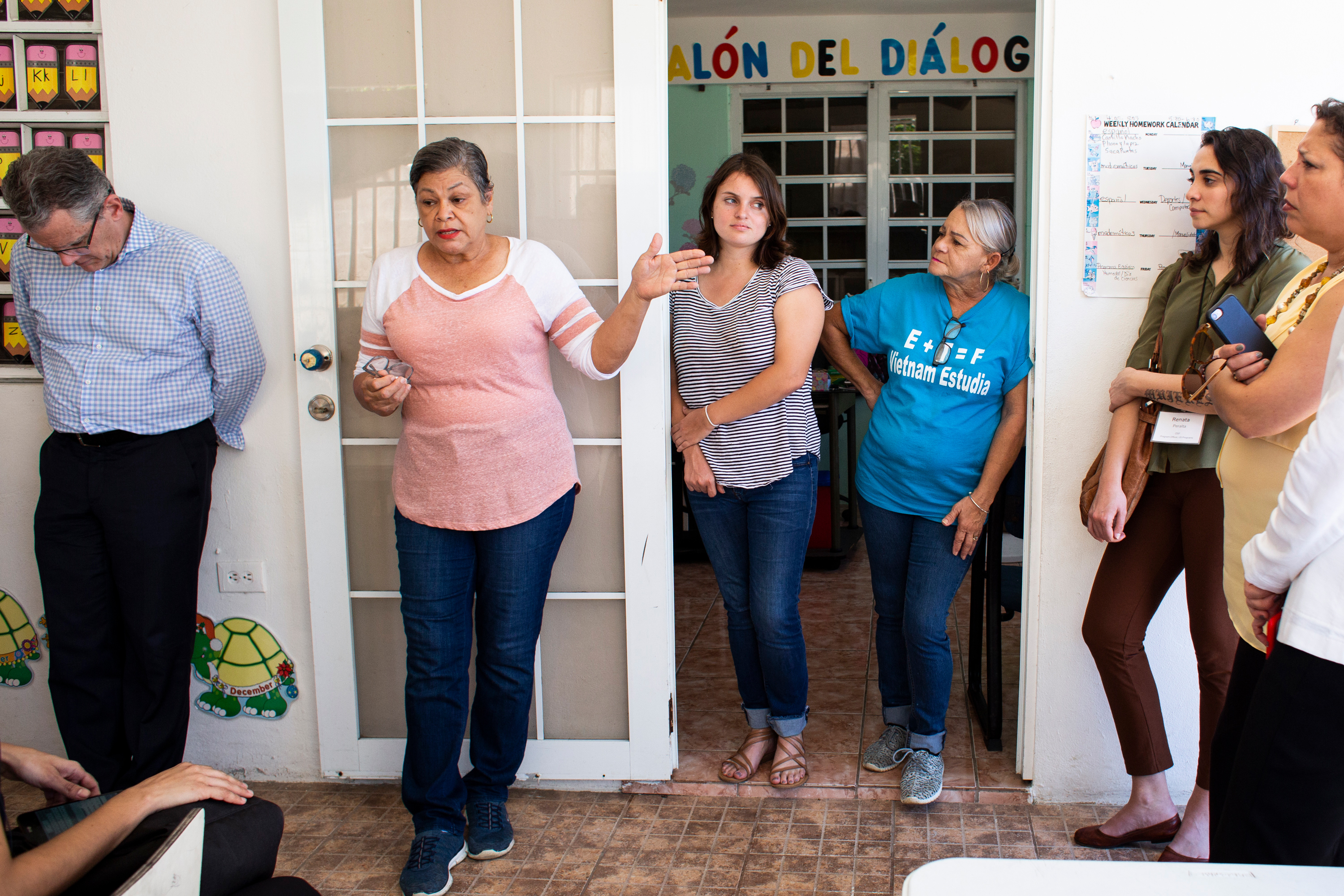 A group of people talking outside of a school room.
