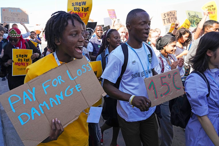 Activists march at the COP27 U.N. Climate Summit in Sharm el-Sheikh, Egypt, on Novemebr 11, 2022. © Peter Dejong/AP Person holding sign saying "Pay for loss and damage" in front of crowd marching