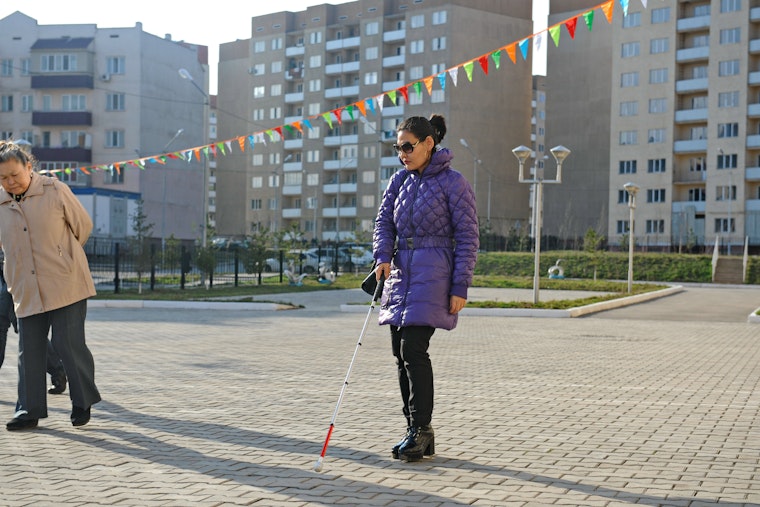 A woman walking with the help of a cane