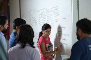 a group of people around a dry erase board