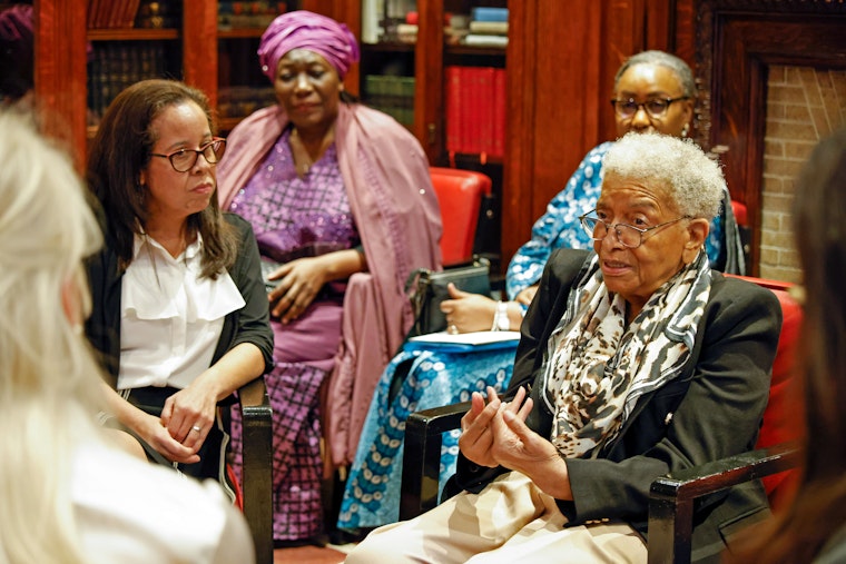 A woman speaks among other women during a dialogue.