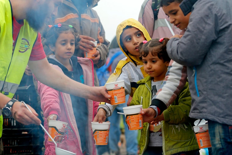 A volunteer distributes food to refugees in Roszke, Hungary. Photo credit: © Laszlo Balogh/Reuters children with soup