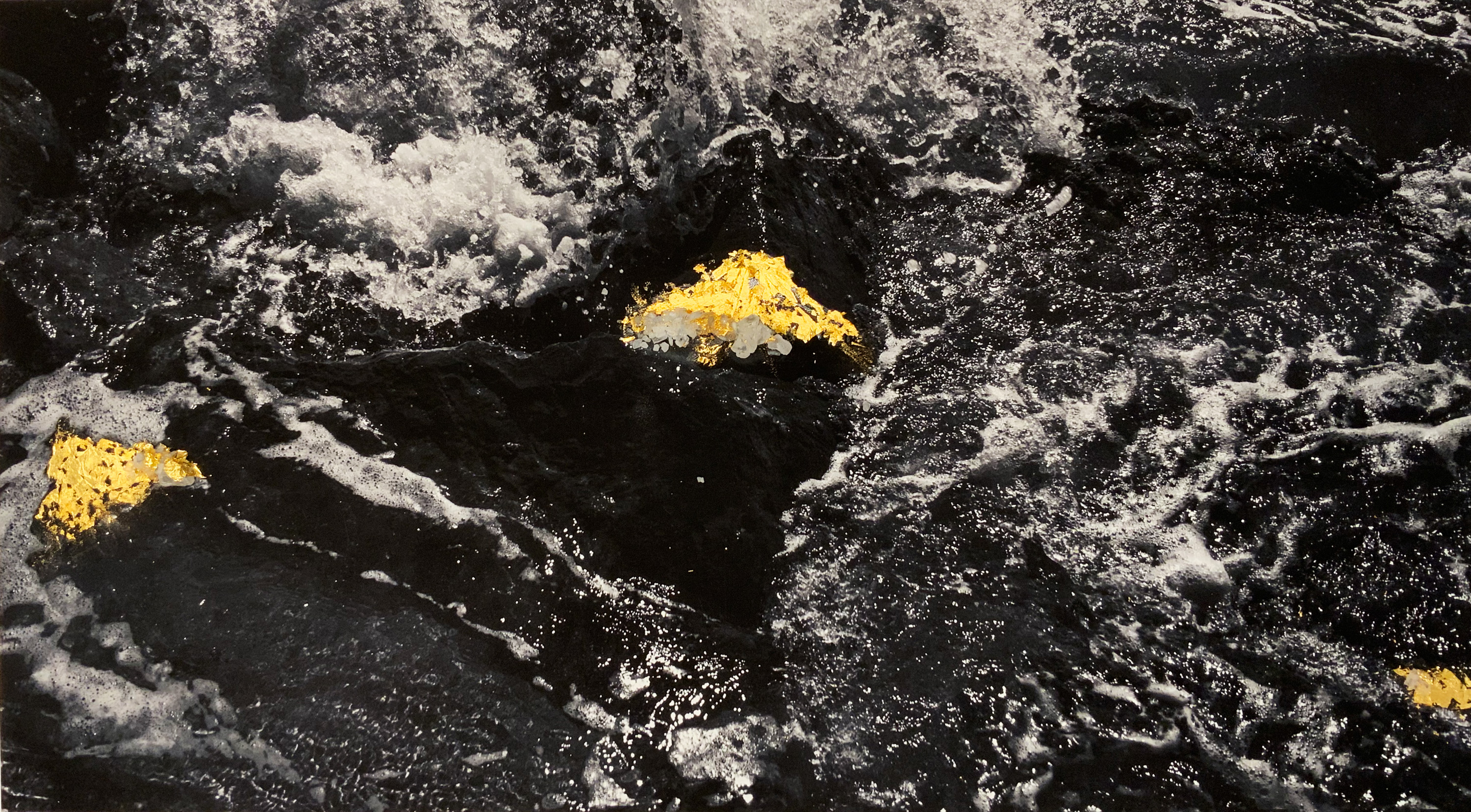 Black and white image of water with collaged gold leaf.