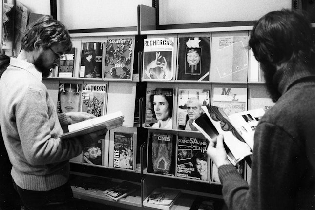 People browsing magazines in front of a rack of periodicals