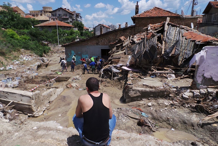 In June 2014, due to the severe rains, flood waters and mud hit the town of Varna, Bulgaria. Varna’s district Asparuhovo was the hardest hit and the heavy rainfall flooded the streets, destroyed homes, and upturned cars. Fourteen people died in the floods, and streets and homes remain buried under layers of mud. According to the city councilor, Radoslav Koev, Asparuhovo was hit by a flash flood from the ridge above the district. Entire sections of Varna have no electricity. Landlines and mobile phones are out of service in certain areas, and the town’s public transportation is seriously disrupted. Photo credit: © Rex Features/Associated Press A man sitting and looking out.