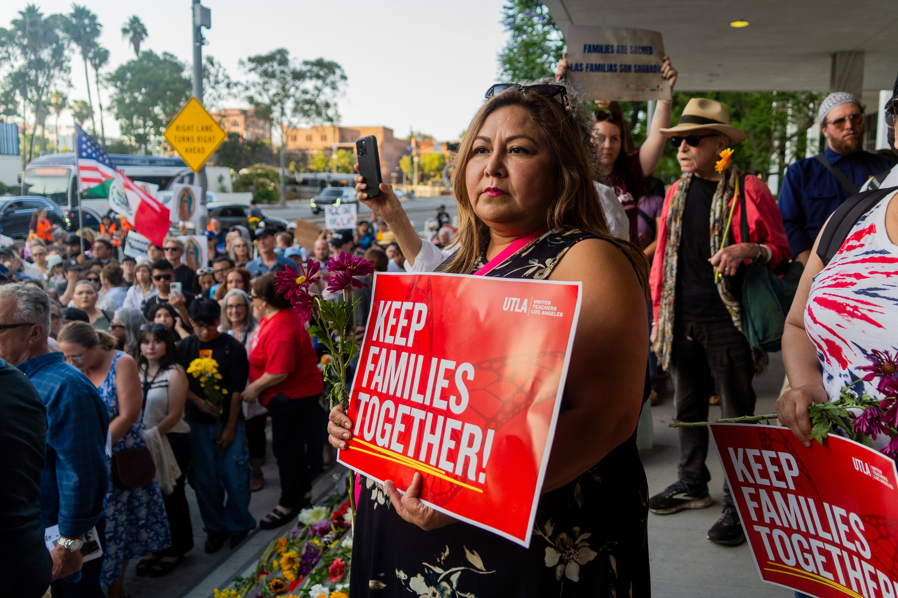 A woman holds a sign that reads "Keep Families Together" in a crowd of people