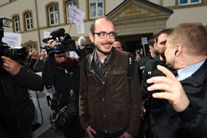 Antoine Deltour, a former employee of PricewaterhouseCoopers, leaves a Luxembourg courthouse on April 26, 2016. Photo credit: © John Thys/AFP/Getty Reporters and police outside a courthouse building