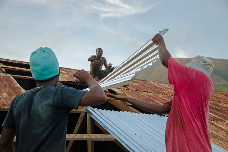Men repair the roof of a home in Haiti following Hurricane Matthew, which left hundreds dead and many more homeless. Photo credit: © Georges Harry Rouzier/Kolektif 2D Three men repairing a roof