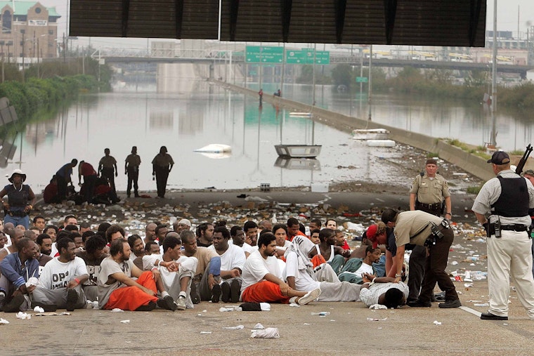 Inmates sitting on a flooded highway