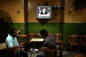 People in a cafe watch President Obama on a TV