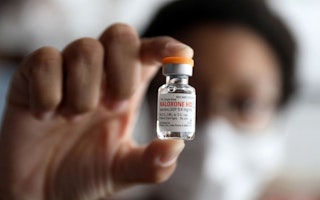 A hand holding a bottle of naloxone