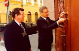 George Soros unlocking a large carved door