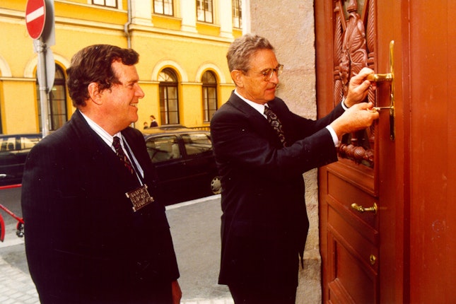 George Soros unlocking a large carved door