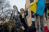 Two people lifting a Ukranian flag
