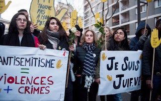 People hold signs at a demonstration against racism in Paris, France.