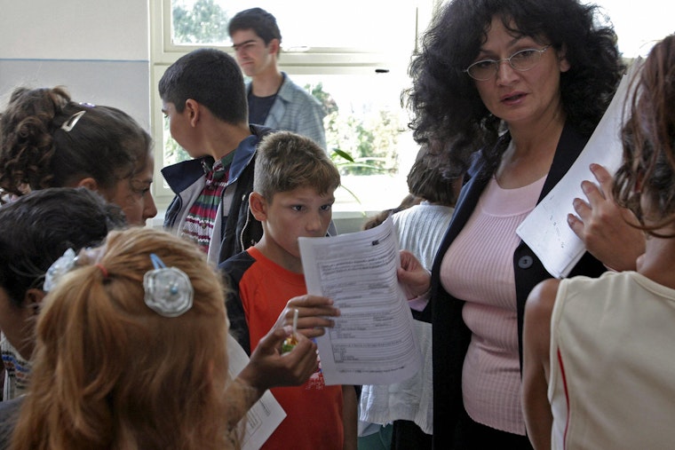 Teacher handing out forms to students