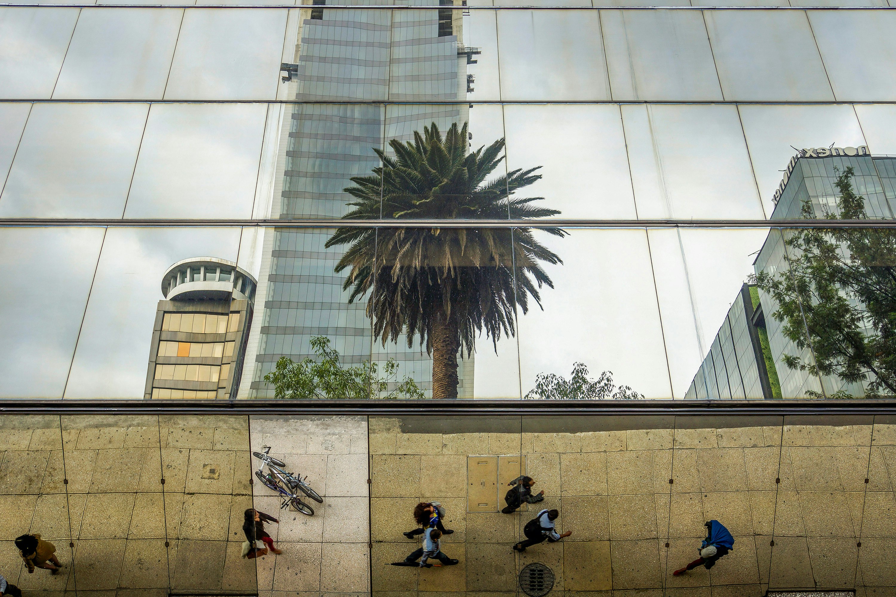 People on the sidewalk next to mirrored buildings in downtown Mexico City.